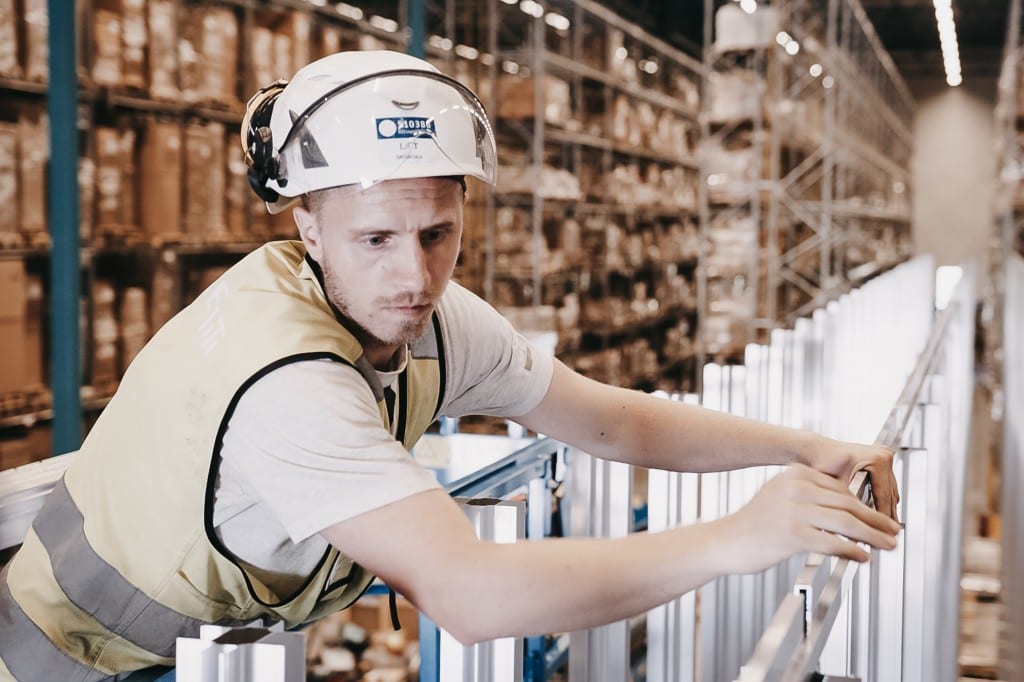 A man in a helmet and yellow vest is constructing the AutoStore grid.