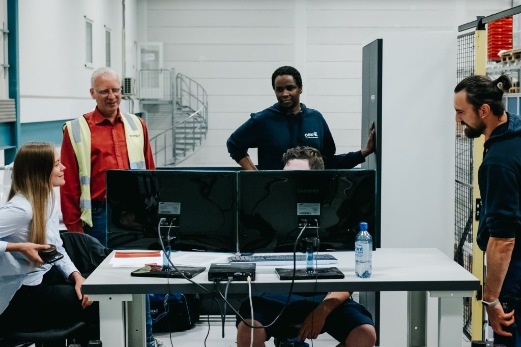 Five people are working together in front of a computer system to learn how to operate the AutoStore-system.