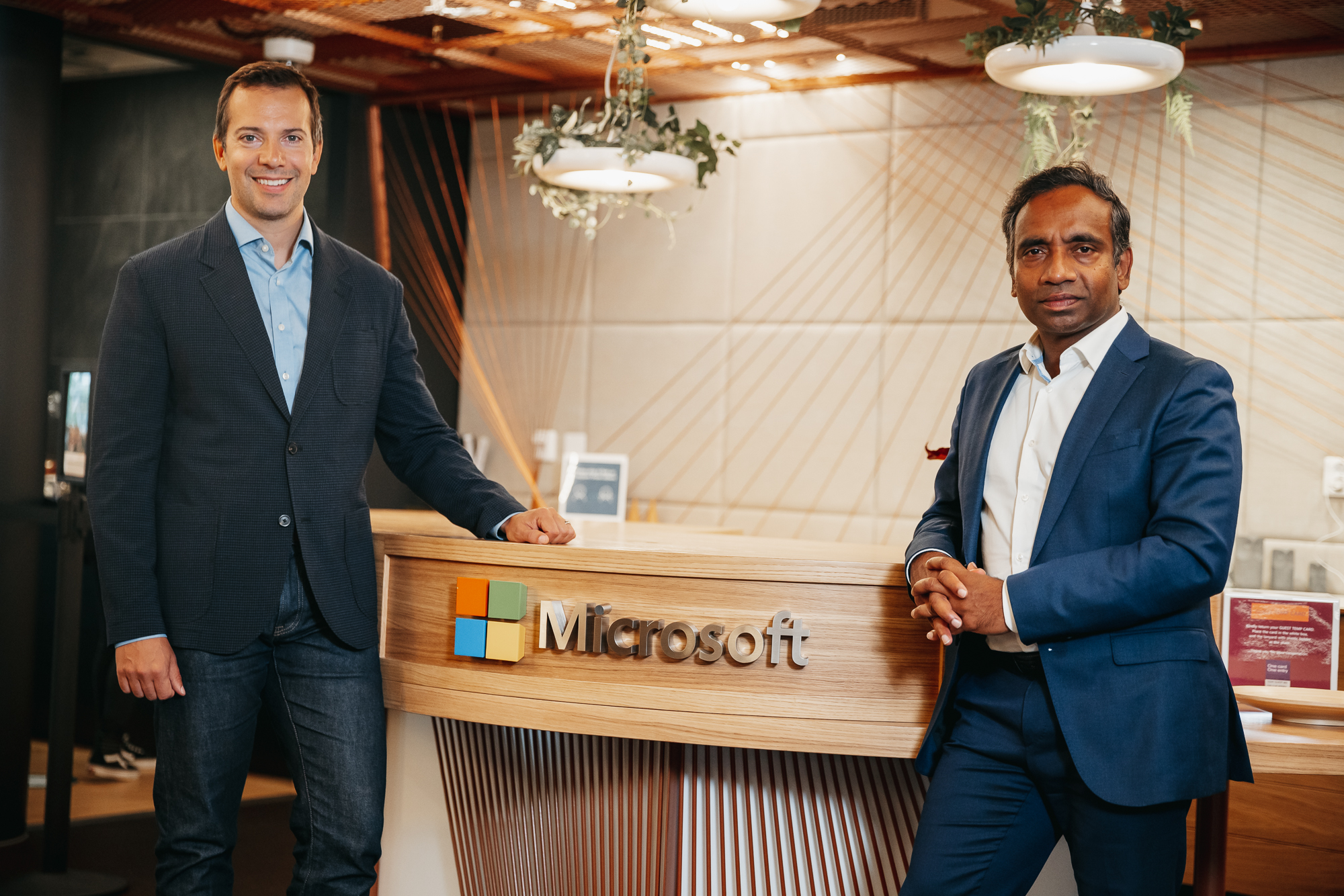 Nadarajah and Reime is smiling to the camera in front of the recepetion desk at Microsoft’s office.