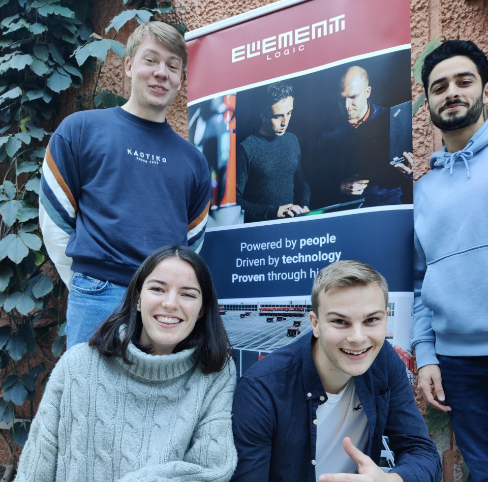 Students smiling to the camera by stand