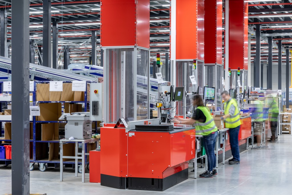 Warehouse workers are operating several AutoStore ports in a busy warehouse.