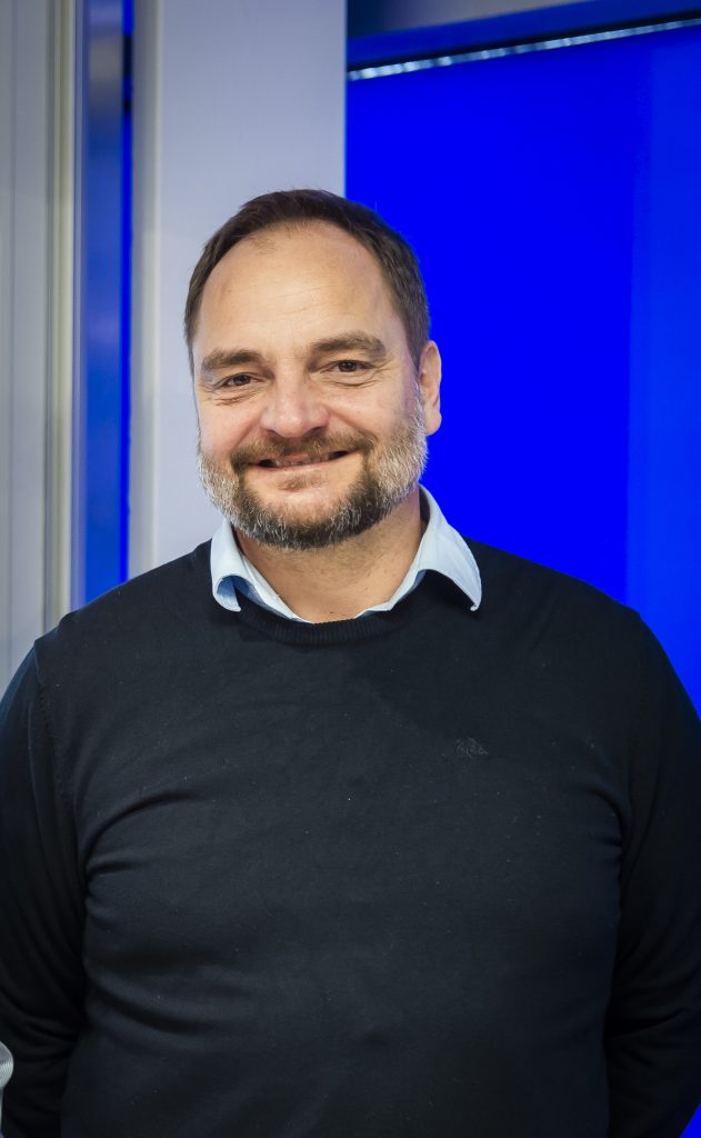 Man smiling beside an AutoStore port